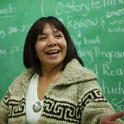 photo of female teacher in front of green chalkboard